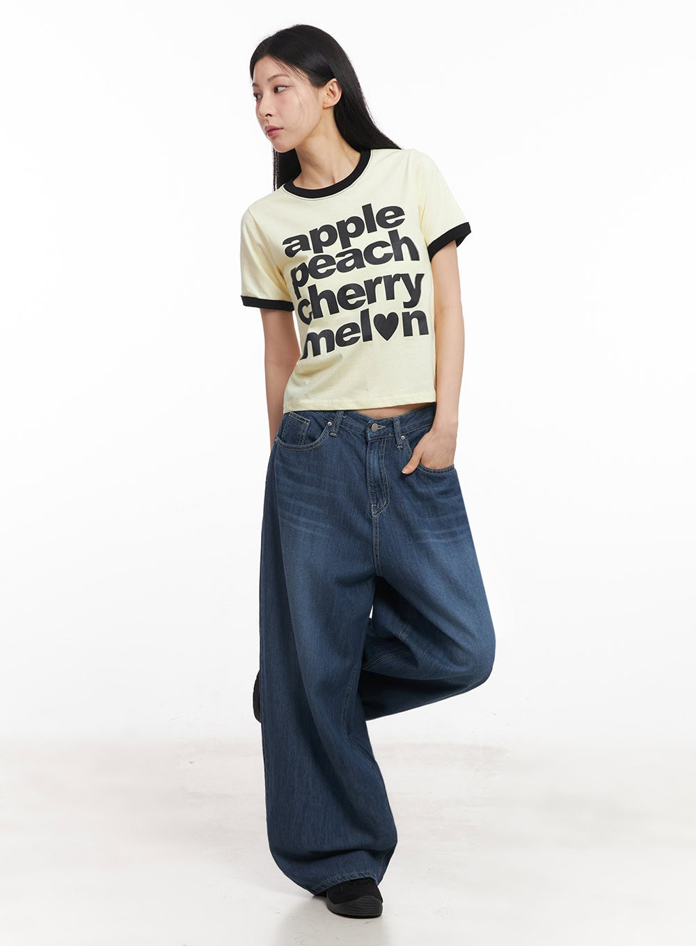 Martha Baggy Jeans IY529 in dark blue, three-quarter front shot on model with one leg raised, wide-leg washed denim with relaxed drape, styled with yellow graphic ringer tee.