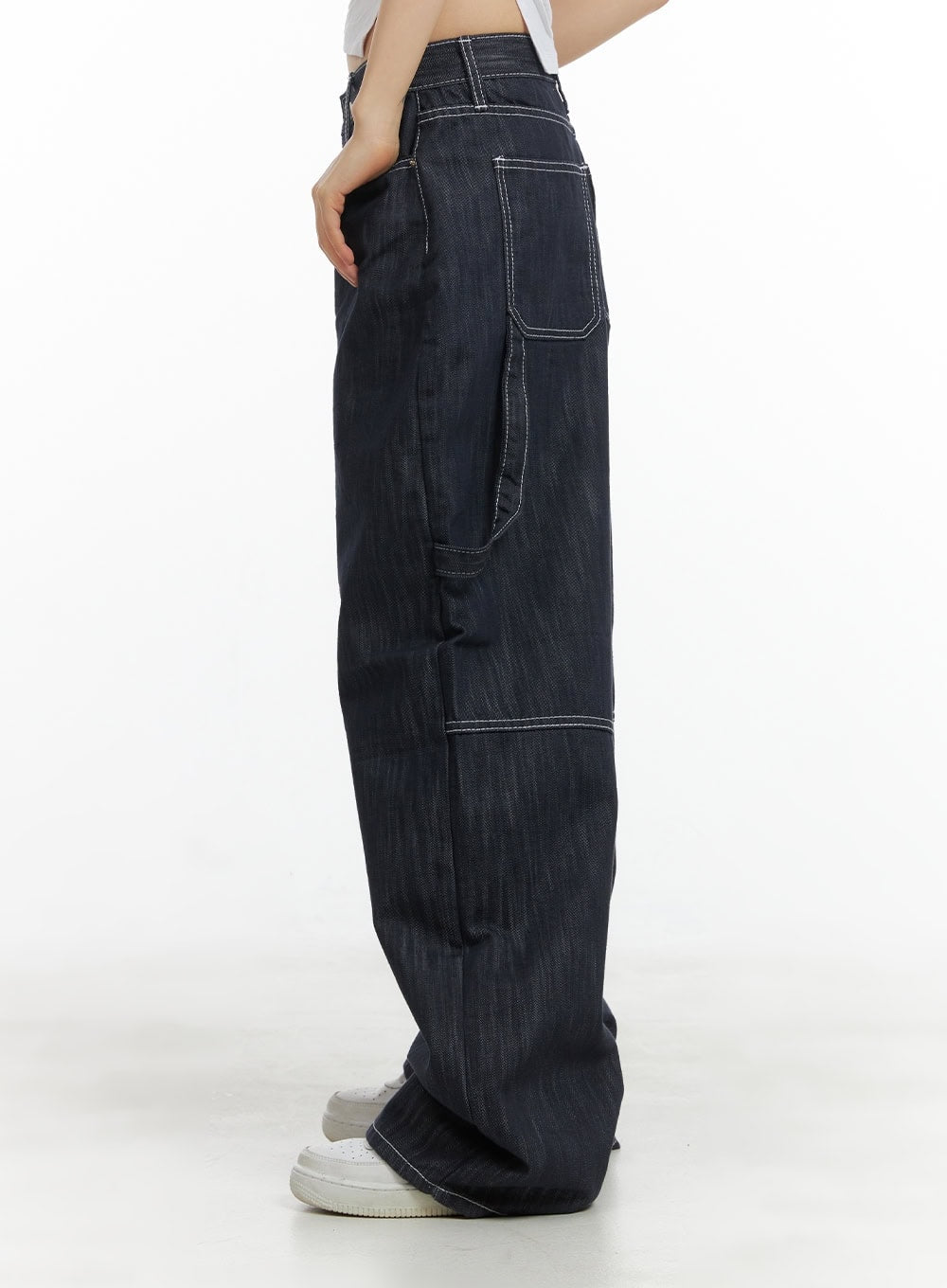 Low-Rise Strap Baggy Jeans CY414 in dark blue, side close-up on model showing thigh pocket placement, contrast white topstitching, and relaxed wide-leg silhouette pooling at hem.