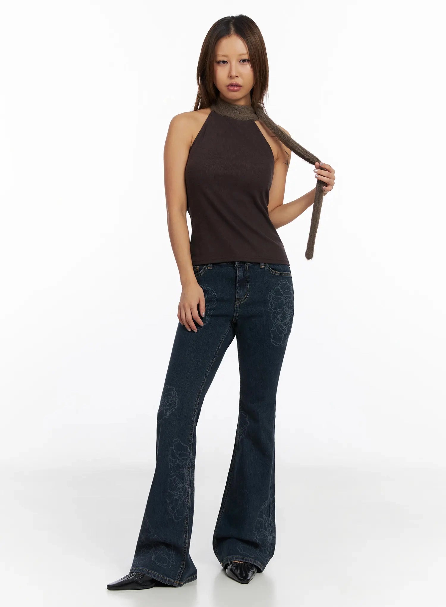 Amari Floral Embriodered Bootcut Jeans IN528 in dark blue, full-length front shot on model, paired with brown halter top and fuzzy neck scarf, floral embroidery visible on thigh, long bootcut silhouette.