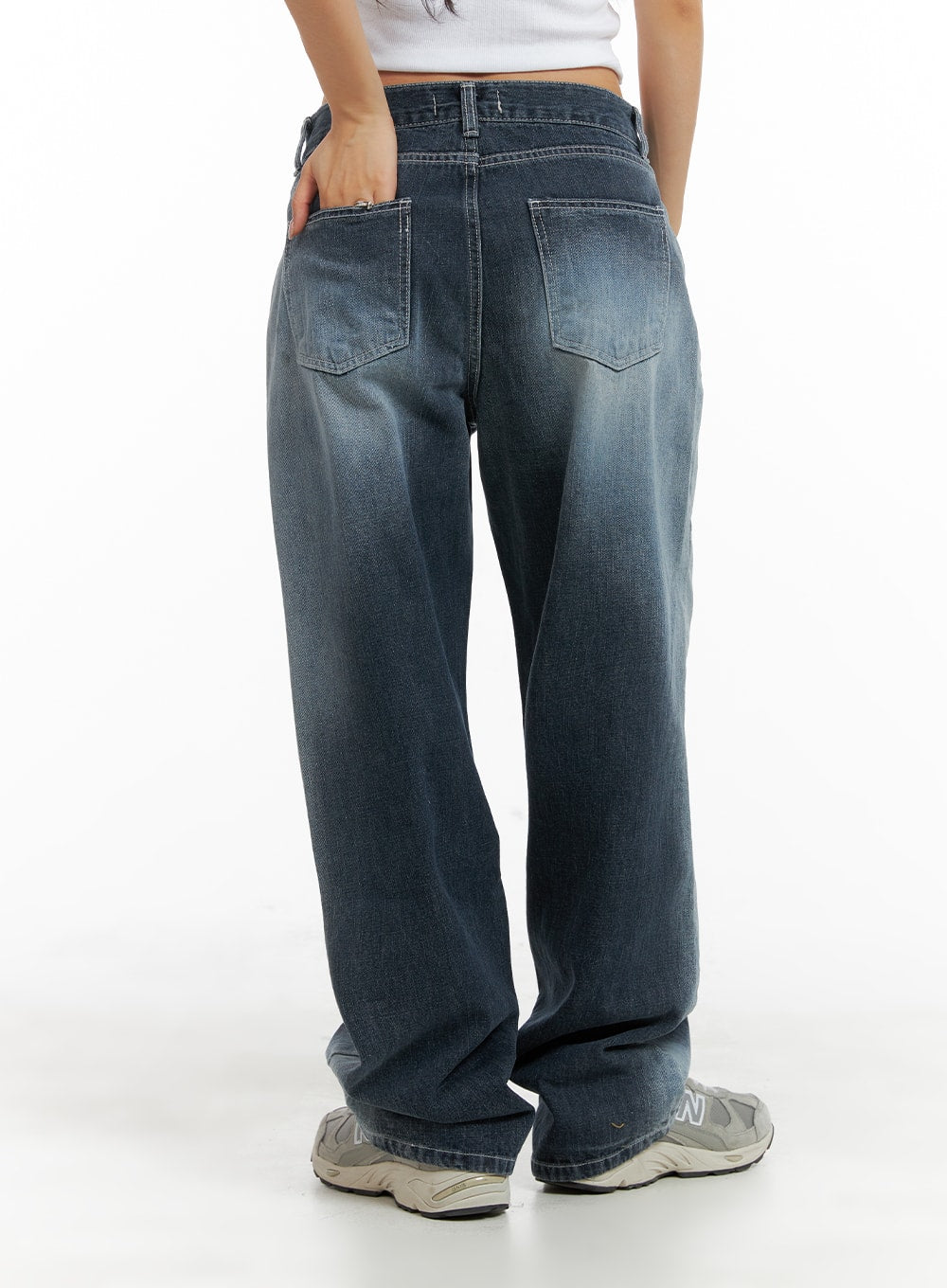 Recycled Wide Baggy Jeans (Unisex) CM425 in dark blue, back view on female model, showing patch back pockets with contrast stitching and washed gradient denim, paired with white crop top and sneakers.