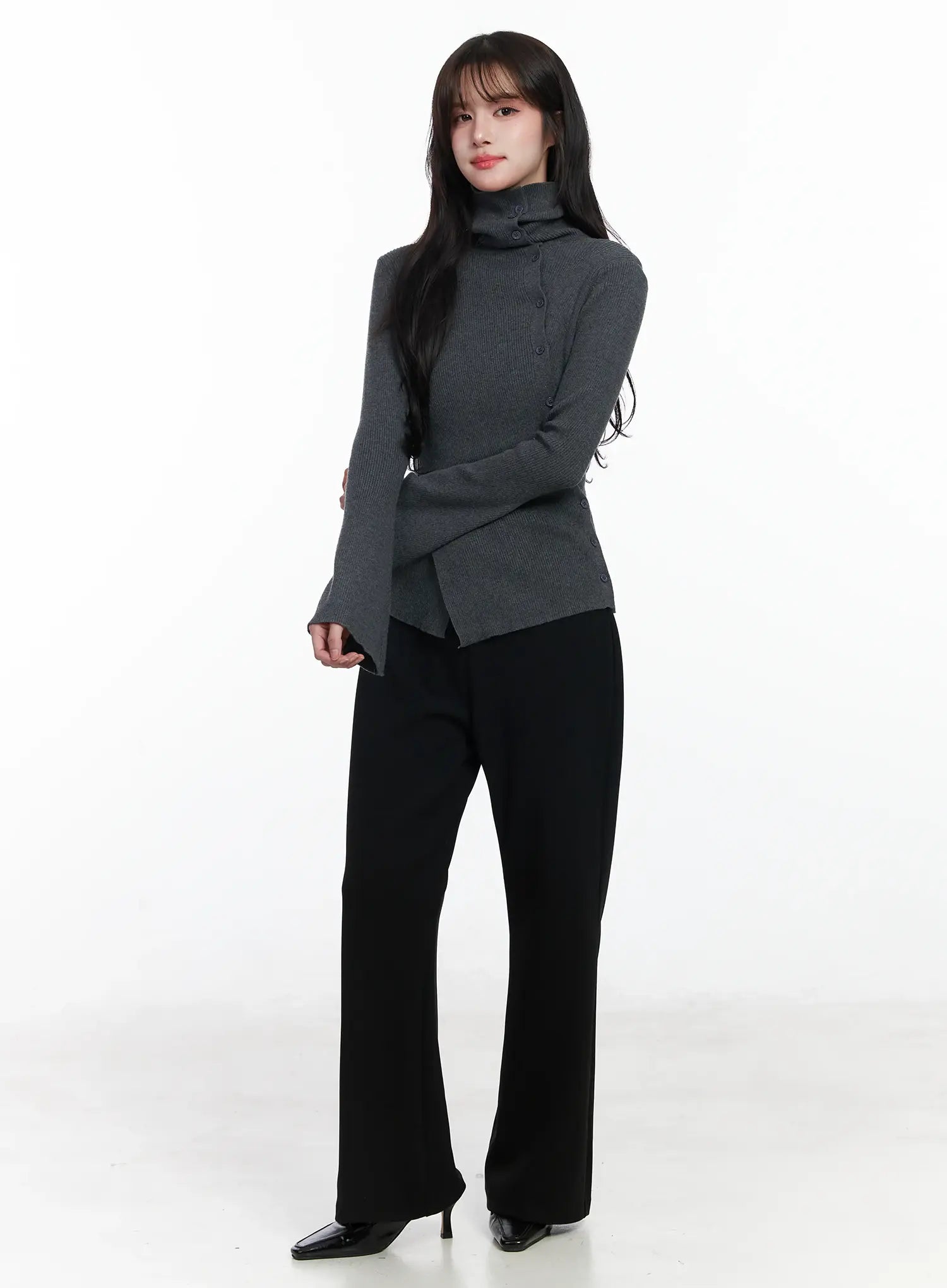 Hip Pad Slacks IJ529 in black, three-quarter front on model, full-length styling with grey turtleneck, slim bootcut silhouette, black heels.