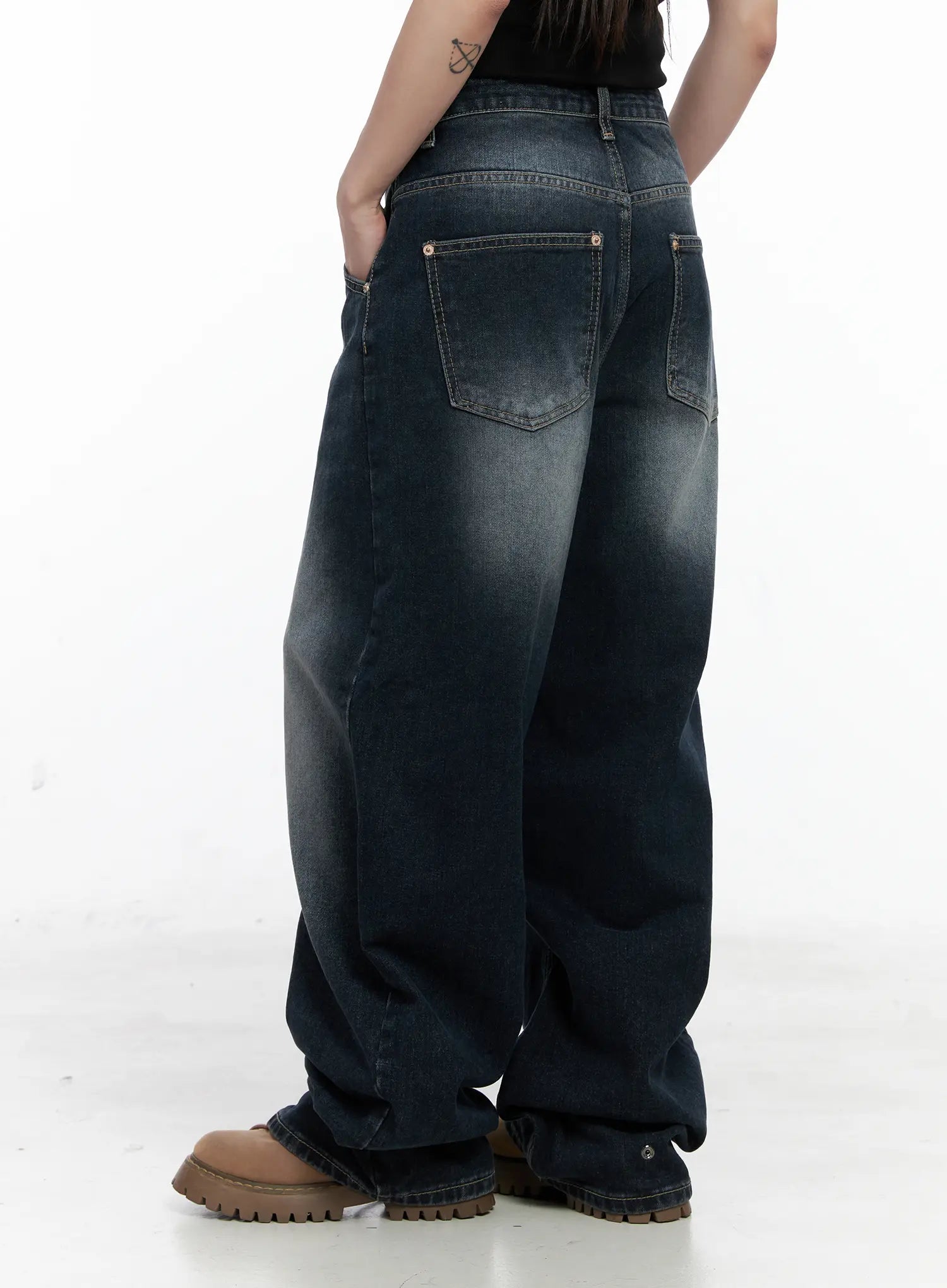 Isla Washed Baggy Jeans CO521 in dark blue, rear three-quarter close-up on model, back pockets with gold rivets and contrast topstitching visible, wide pooling hem on chunky boots.
