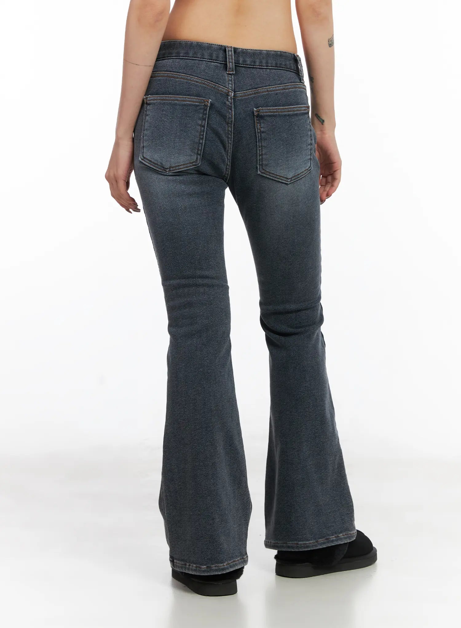 Kiera Low-Rise Fleece-Lined Bootcut Jeans CD509 in washed dark blue, back view on model, twin back pockets with contrast stitching, low-rise waistband, wide flared hem pooling at boots.
