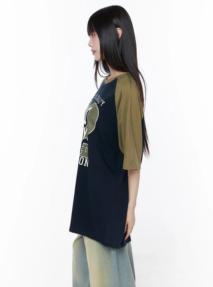 Casual Loose Fit Graphic Tee CU519 in dark blue, side profile close-up on model, showing graphic print on front, olive contrast raglan sleeve, oversized boxy cut with straight hem.