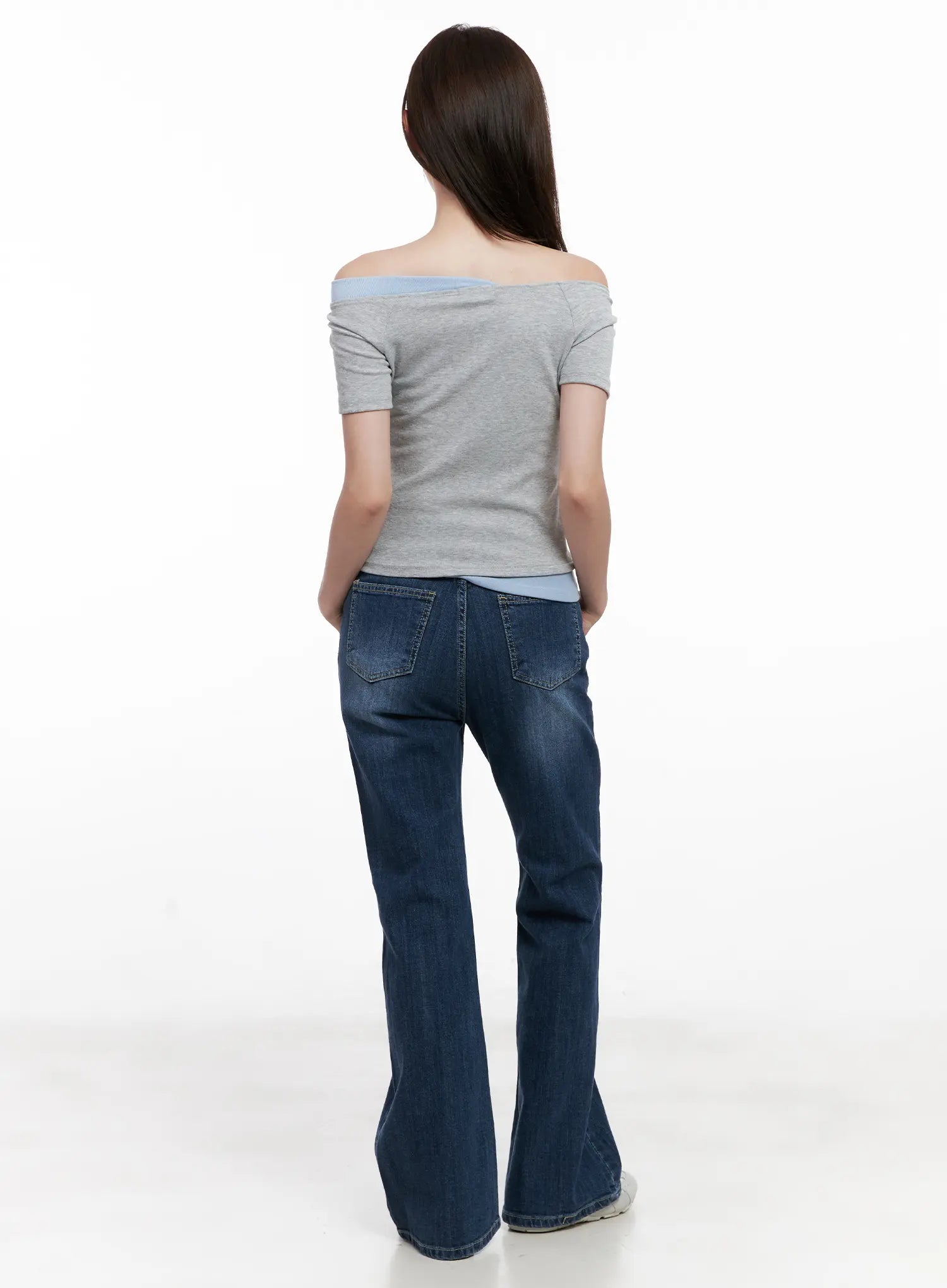 Solhee Classic Flare Denim Jeans CL524 in dark blue, full back shot on model, flared hem and back pocket detail visible, styled with grey off-shoulder top and white sneakers.