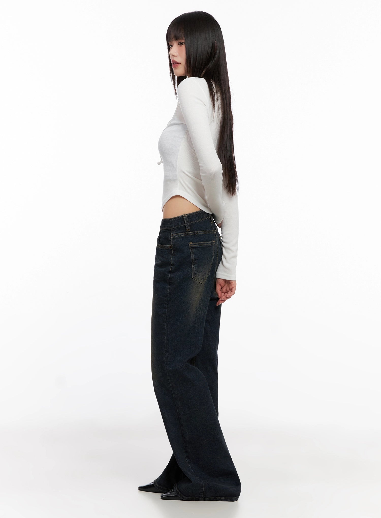 Lyanna Vintage Wash Bootcut Jeans IN503 in dark blue, side view on model, profile showing slim thigh to wide bootcut flare, paired with white long-sleeve crop top.