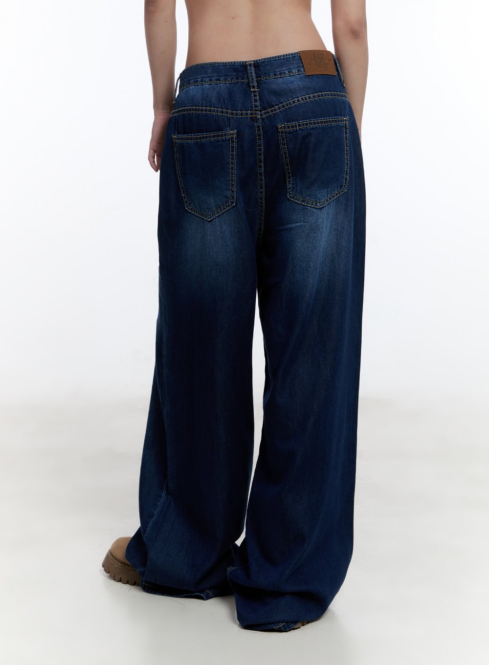 Jill Baggy Jeans CY530 in dark blue, back close-up on model, showing dual back patch pockets with contrast stitching, leather logo patch, and washed denim texture.