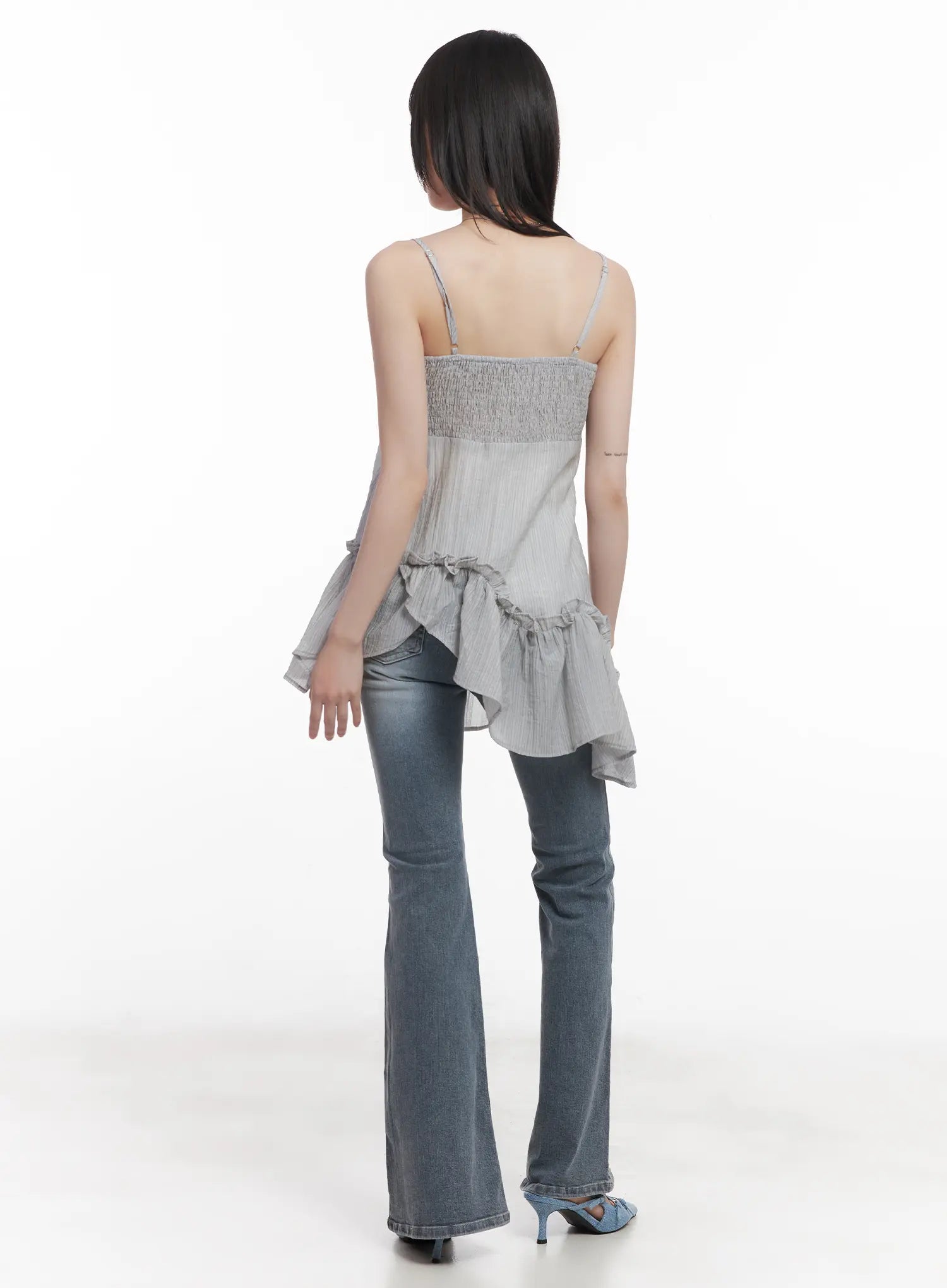Soyeon Flared Jeans with Hip Pads CU520 in dark gray, back full-body on model, washed flared denim showing rear pocket detail, paired with ruffle cami and blue denim heels.