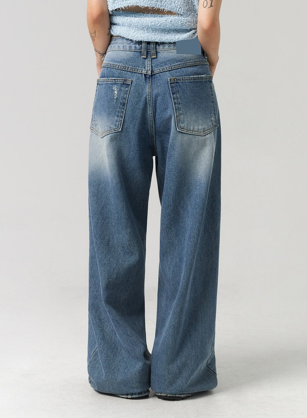 Baggy Jeans CL313 in washed blue, back view close-up on model, showing dual back patch pockets, slight distressing, wide-leg hem, and gradient washed cotton denim.