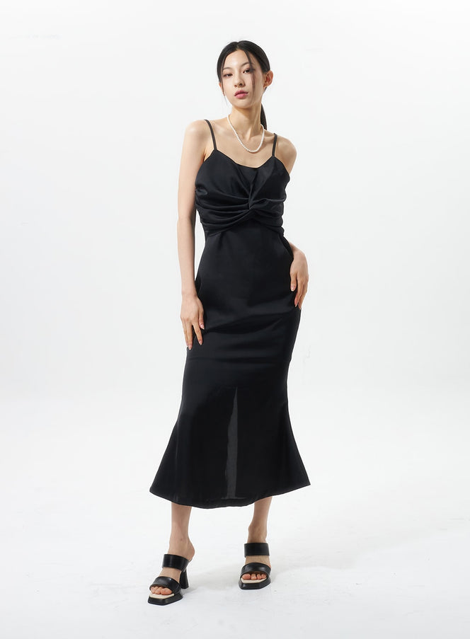 LEWKIN Cross Bust Satin Maxi Dress IU326 in black, front full-length on model, slim satin camisole maxi with cross-bust shirring, flared hem, styled with pearl necklace and black slides.