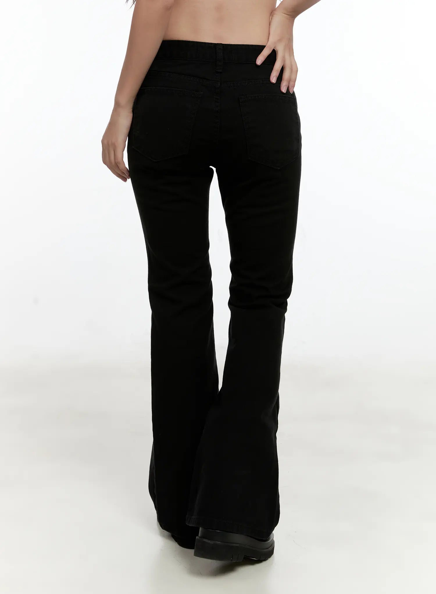 Classic Flare Pants CL531 in black, back close-up on model, showing back pockets, belt loop waistband, and flared hem sweep in smooth cotton denim.