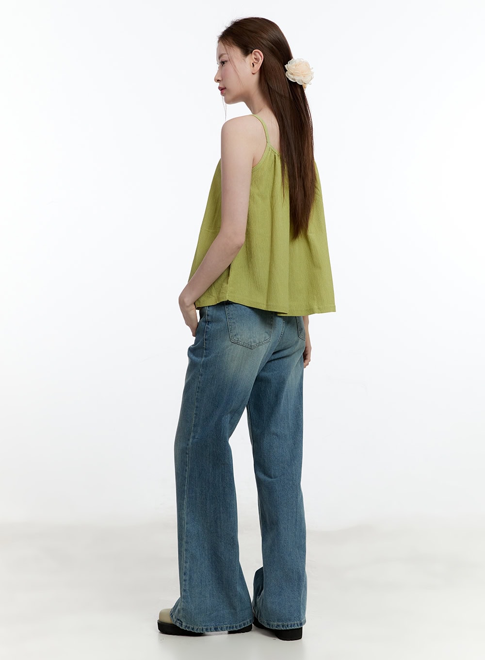 Aleks Relaxed-Fit Flared Jeans CM521 in blue, three-quarter back view on model, back pockets and flared hem visible, styled with green cami top and flower hair clip.