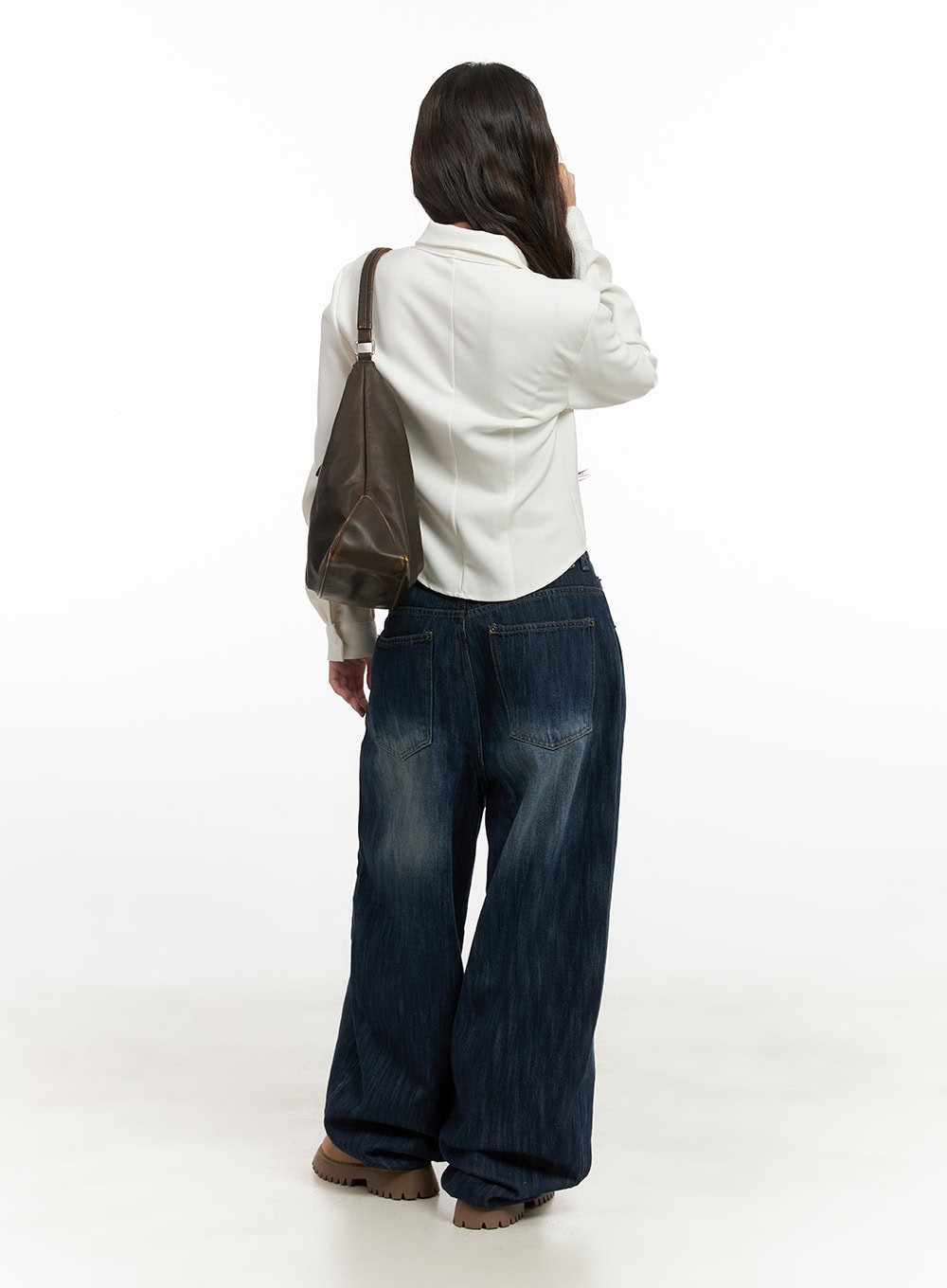 Jessica Wide-Fit Denim Jeans CN426 in blue, full-body back shot on model carrying brown tote, wide-leg hem pooling at floor, washed indigo cotton denim, paired with white shirt.