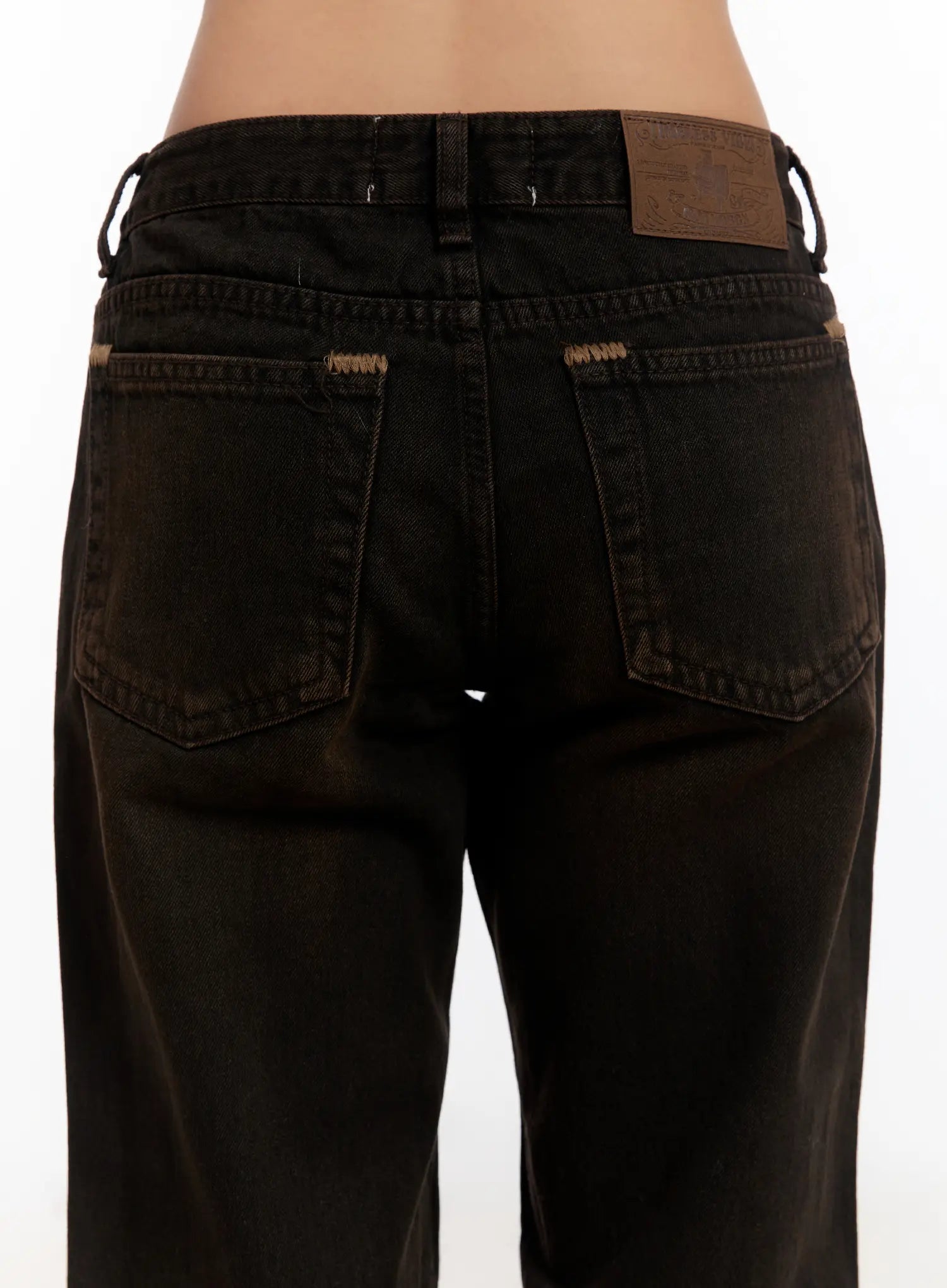 Mael Low Rise Straight Jeans CN527 in black, back waist close-up on model, showing dual back pockets with tan contrast stitching, leather patch label, and belt loops.
