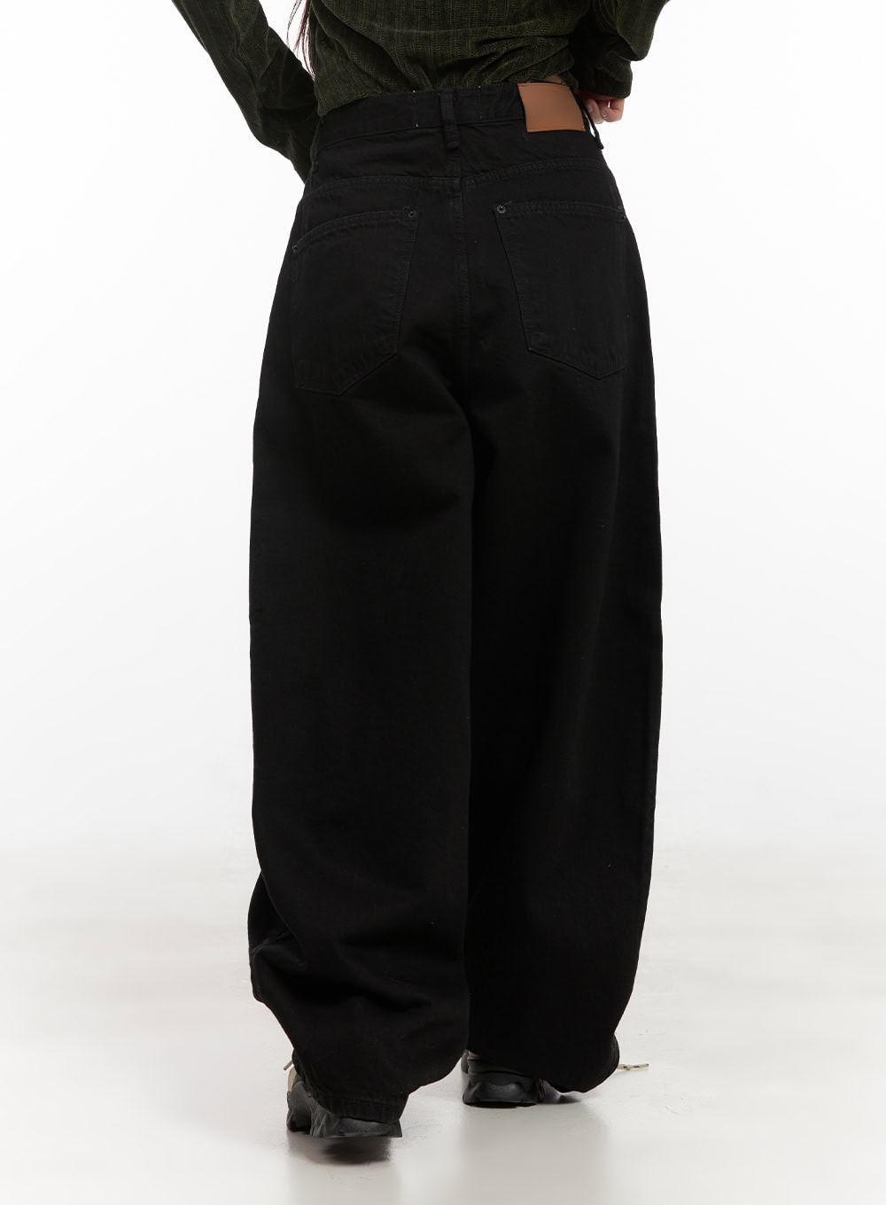 Yasmin Denim Wide Fit Jeans CD413 in black, rear close-up on model, back yoke and dual patch pockets visible, voluminous wide-leg drape pooling at hem, paired with green ribbed top.