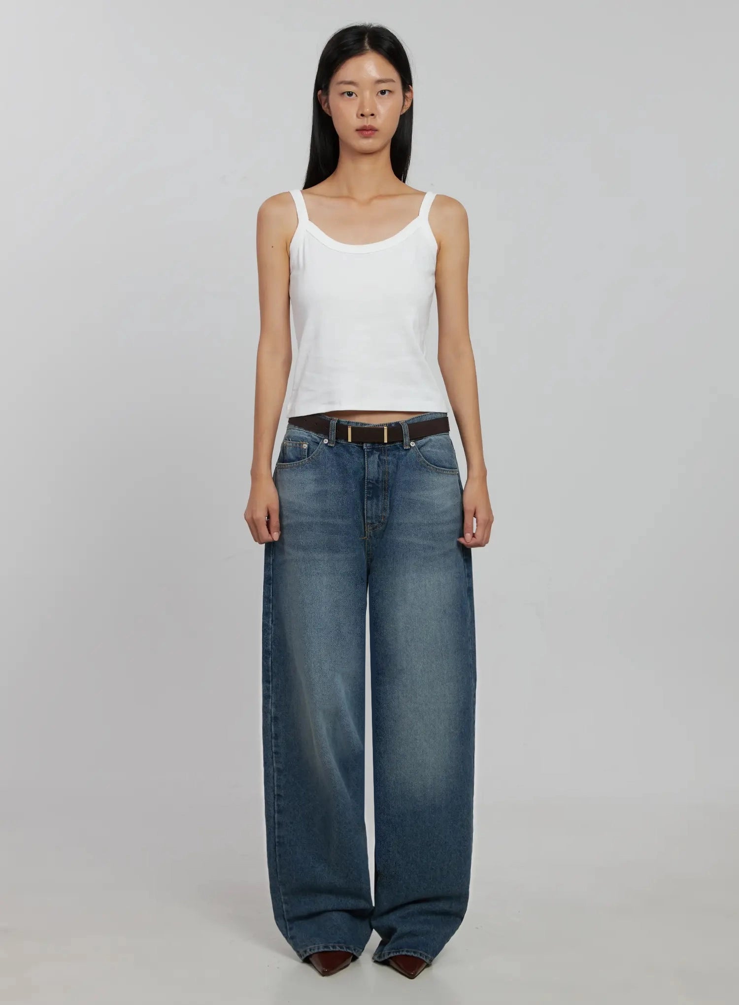 Akira Wide Leg Jeans IJ508 in blue, full-body front on model, long wide-leg washed denim with brown belt, paired with white crop cami and burgundy boots.