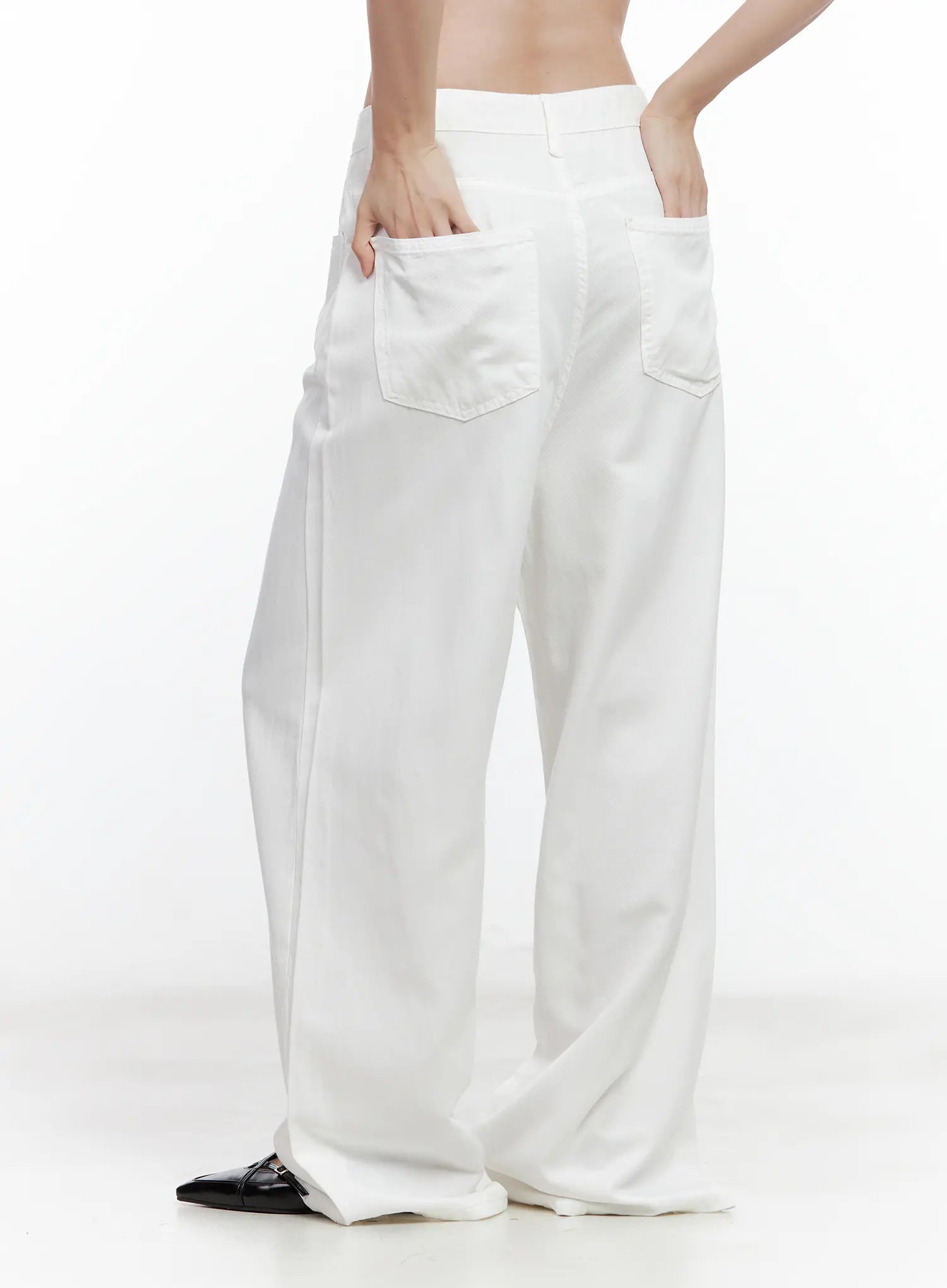 Jennie Baggy Wide-Leg Jeans CL502 in white, rear three-quarter close-up on model, highlighting large square back pockets and roomy baggy wide-leg cotton drape, hand in pocket.