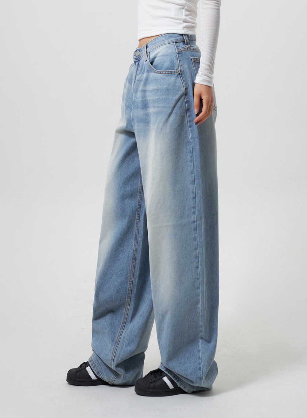 Low Rise Baggy Jeans CY324 in light blue, side-angle close-up on model from waist down, wide-leg silhouette with faded denim wash and side seam detail, paired with white long-sleeve top.