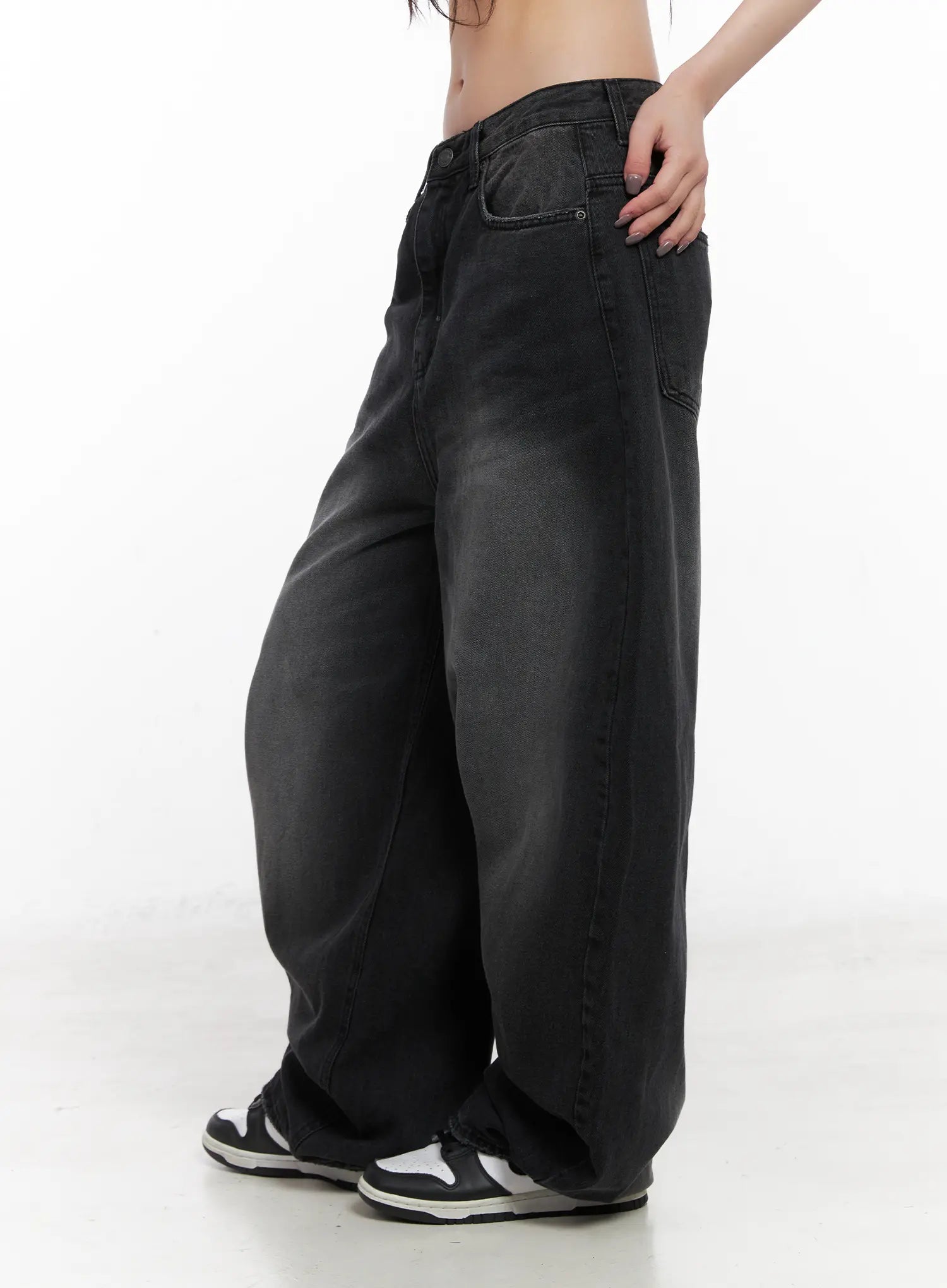 Yuji Dark-Washed Baggy Jeans CN513 in black, close-up side shot from waist to ankle on model, highlighting exaggerated wide-fit silhouette, faded wash gradient, and side pocket detail with white sneakers.