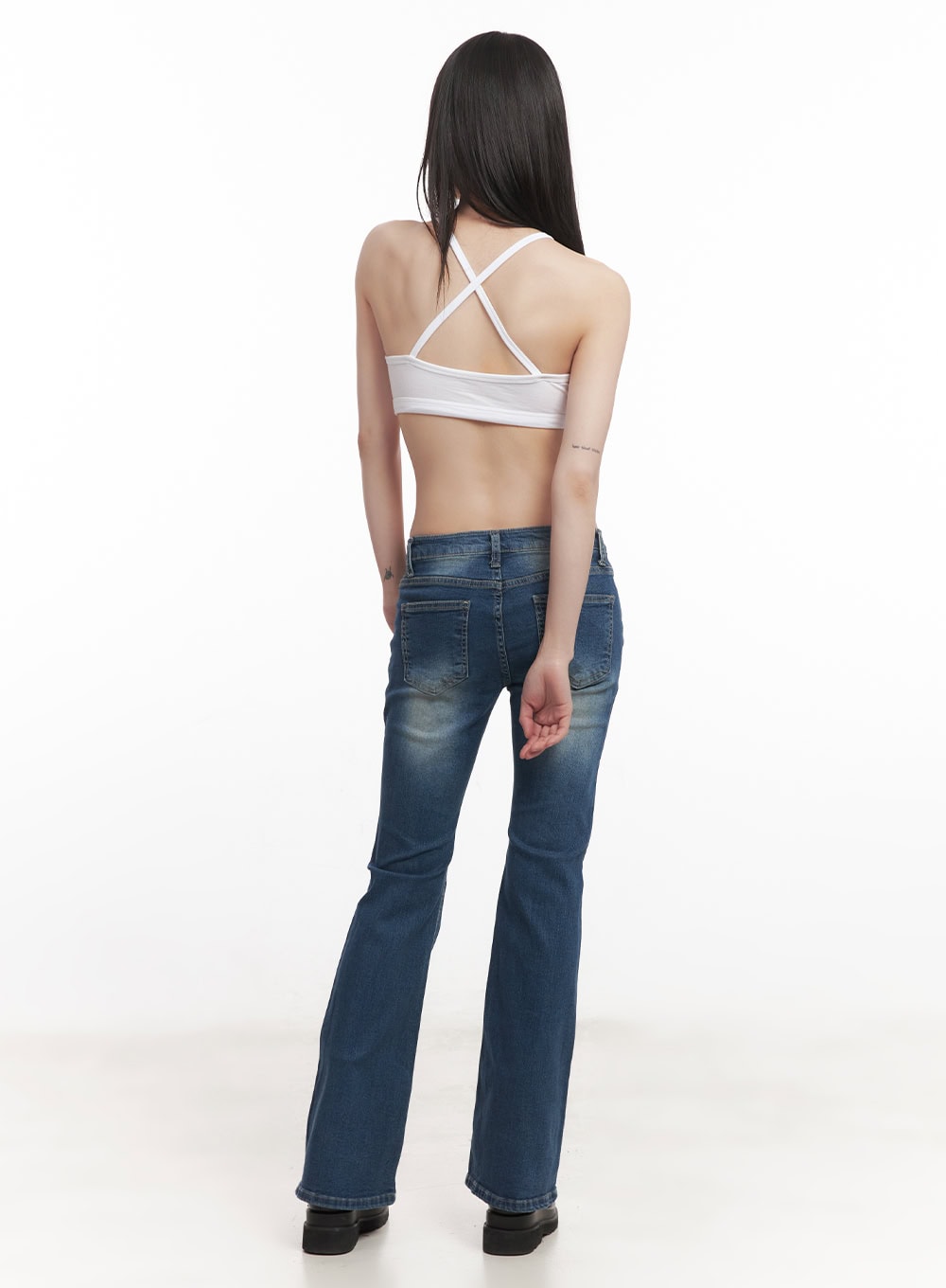 Rebecca Low-Waist Flared Jeans CM519 in dark blue, full-body back view on model in white cross-back bralette, showing back pockets and subtle bootcut flare with washed finish.