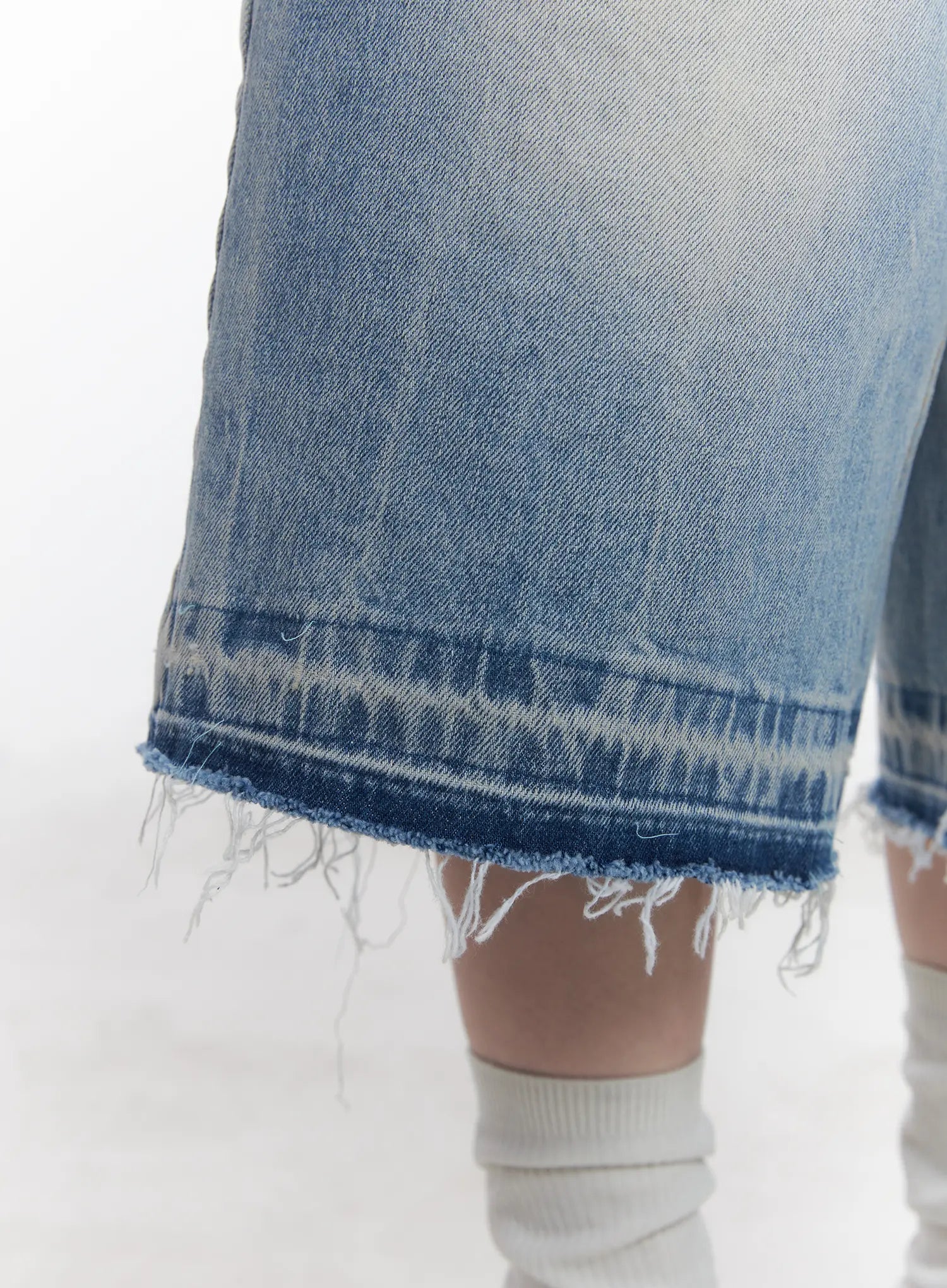 Light Wash Vintage Jorts CU519 in blue, extreme close-up of raw frayed hem detail, contrast dark selvedge stitch line with distressed fringe edge on light washed cotton denim.