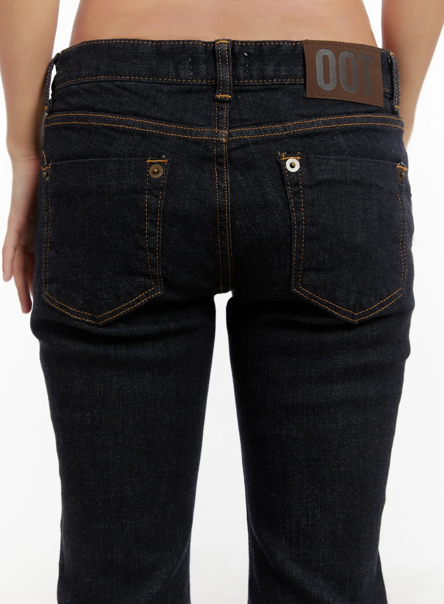 Adalee Non-Fade Low-Rise Flare Jeans CD515 in dark indigo, back close-up detail shot showing dual back pockets with gold contrast stitch, leather patch label, and rivet hardware.
