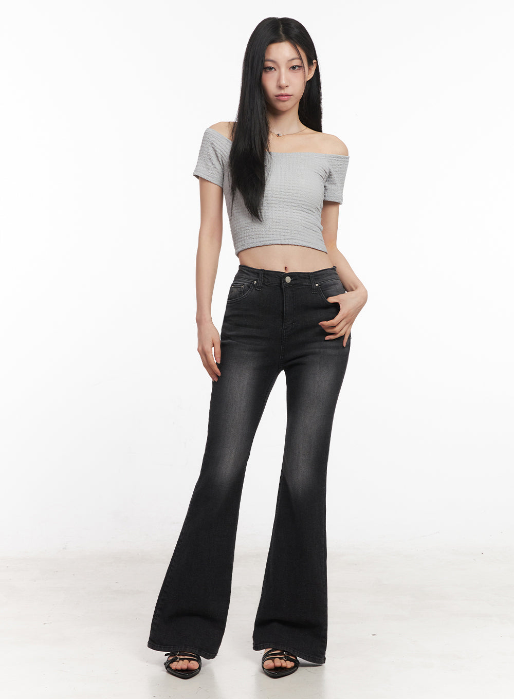 Lior Slim-Fit Bootcut Jeans IY516 in black, full-length front shot on model with hand on hip, washed slim-fit bootcut denim, high-rise, styled with grey crop top and black strappy heels.