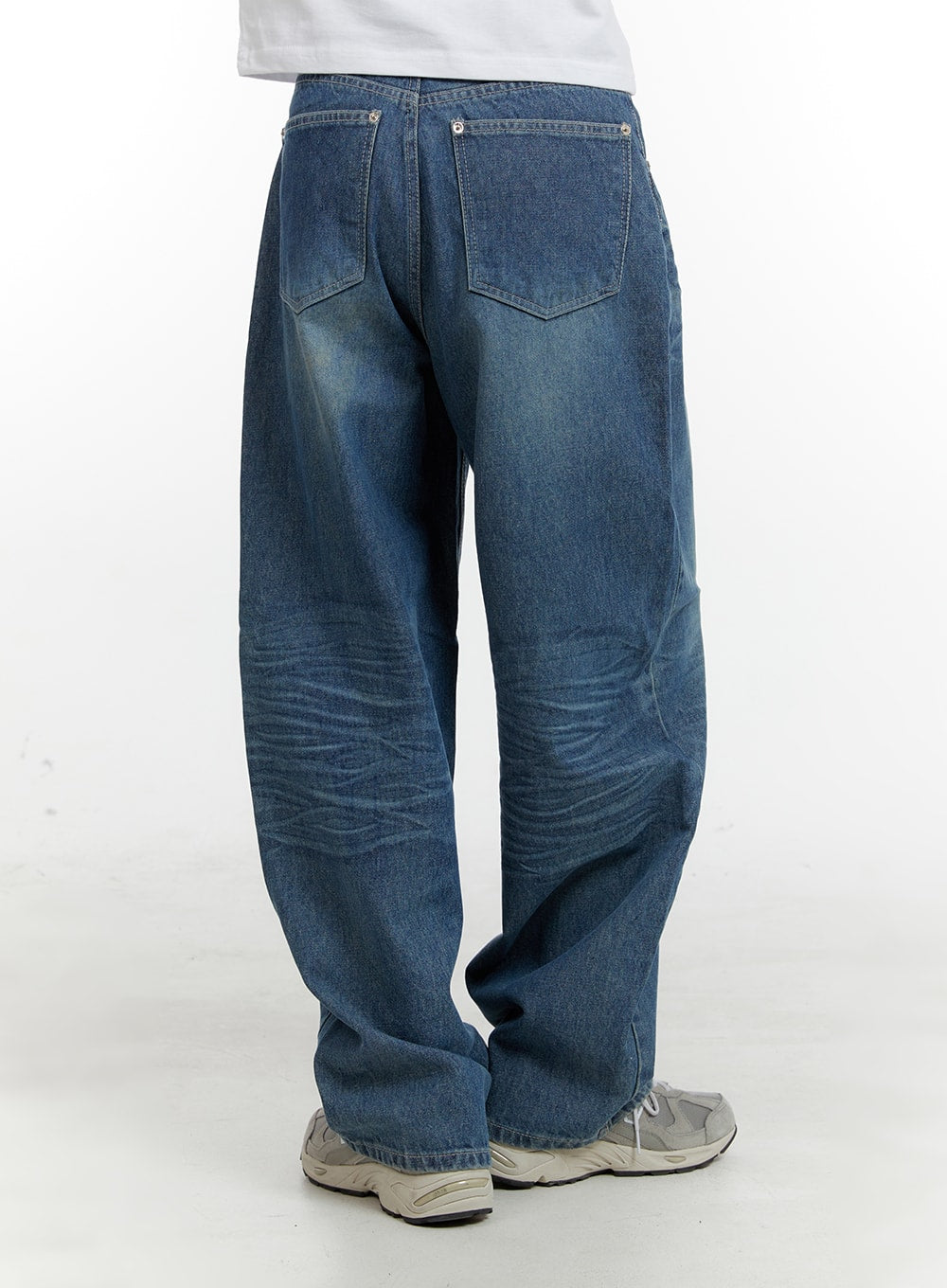 Wide Fit Baggy Jeans CA401 in blue, back view on model, washed denim with dual back pockets, silver rivets, and wide baggy leg, paired with grey sneakers.
