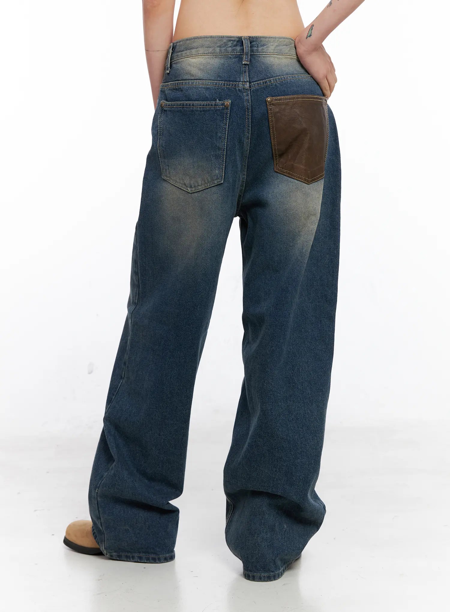 Xyla Vintage Pocket Baggy Jeans CO507 in blue, back view on model, wide-leg washed cotton denim with brown leather back pocket detail and vintage fading, tan boots.
