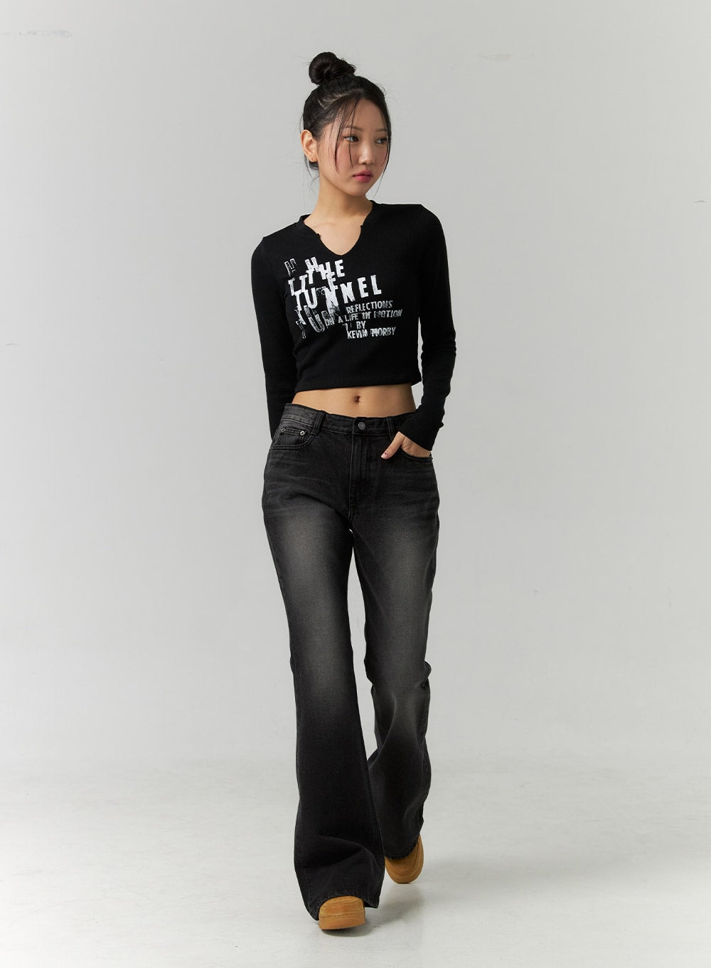 Low Rise Bootcut Jeans CD304 in black, full-length front view on model mid-stride, washed black denim with low waist and flared bootcut silhouette, styled with black crop top.