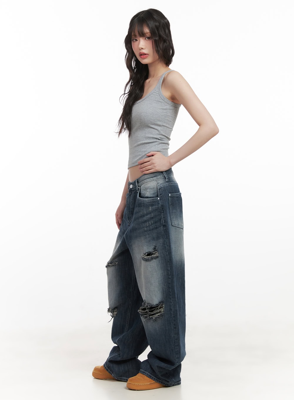 Alison Destroyed Baggy Jeans CJ523 in dark blue, full-body side shot on model in gray crop tank, showing wide baggy silhouette, washed fade, and multiple destroyed rip openings.