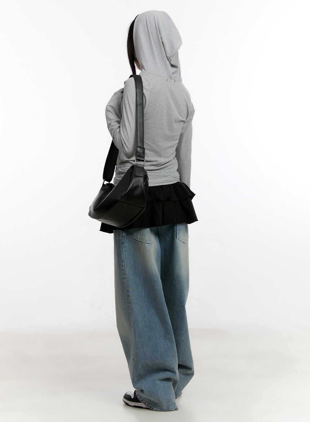 Jillie Washed Baggy Jeans CA508 in blue, back 3/4 view on model with hood up, wide-fit washed denim with voluminous leg, styled with striped hoodie and black leather shoulder bag.