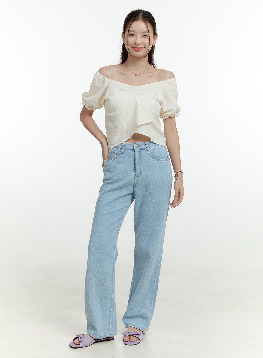 Ava Light Washed Straight Jeans OL430 in light blue, front full-length smiling pose on model, wide-fit high-rise straight leg, light washed casual denim, styled with ivory off-shoulder top and lavender bow slides.
