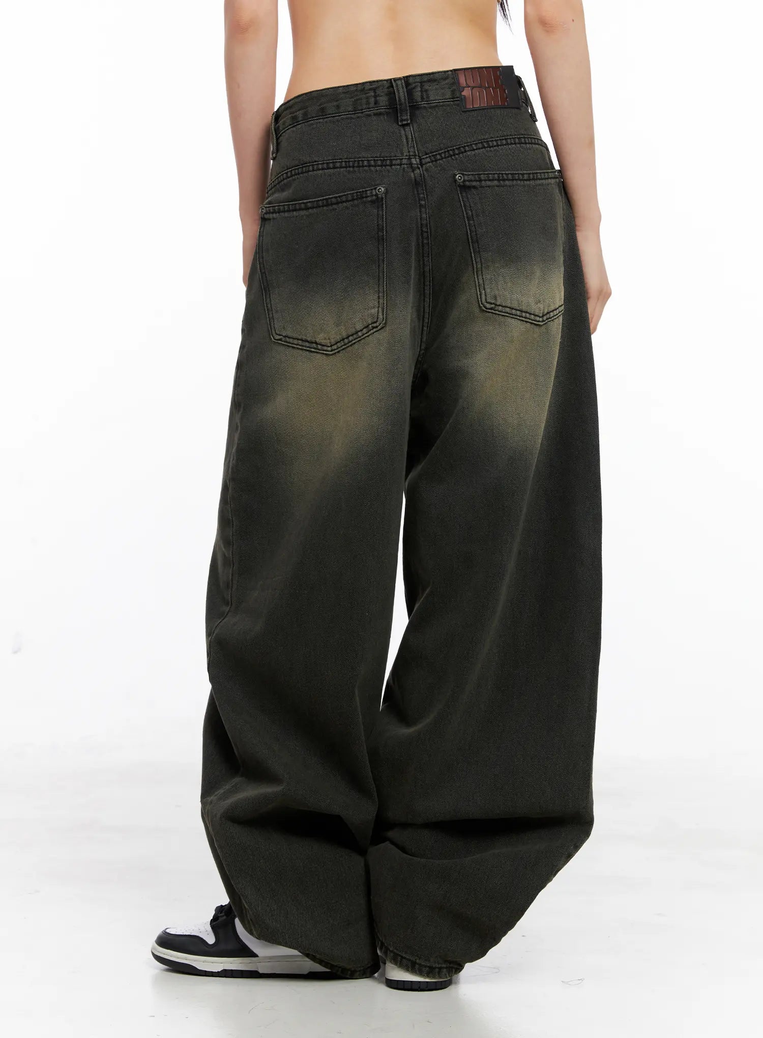 Elias Mega Wide Vintage Washed Jeans CC1109 in black, back view on model, showing dual back pockets with contrast stitching, branded patch, and yellow-toned vintage wash on wide cotton denim.