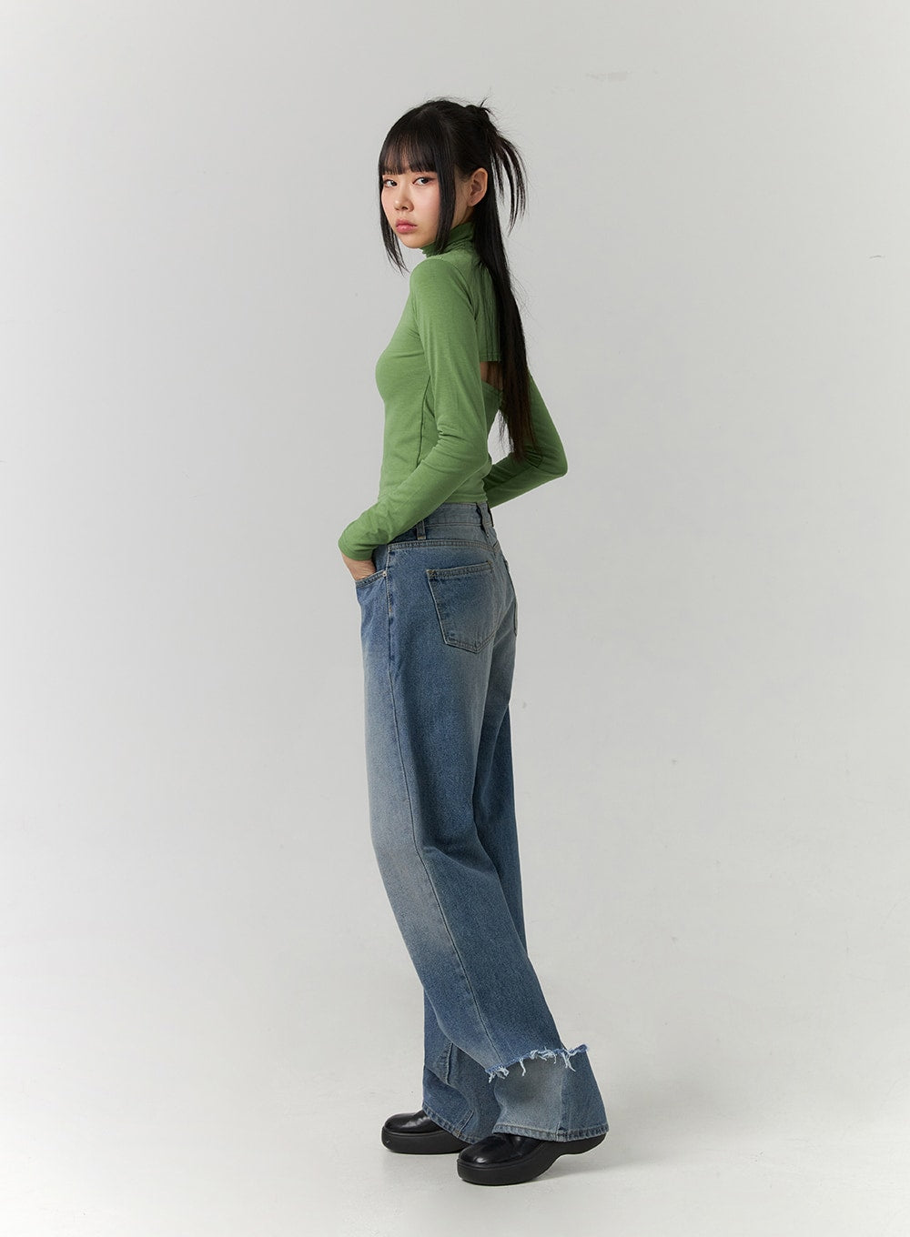 Ripped Straight Leg Jeans CD308 in blue, three-quarter back-side view on model, wide-fit washed denim with ripped frayed ankle hem, paired with green turtleneck crop top.