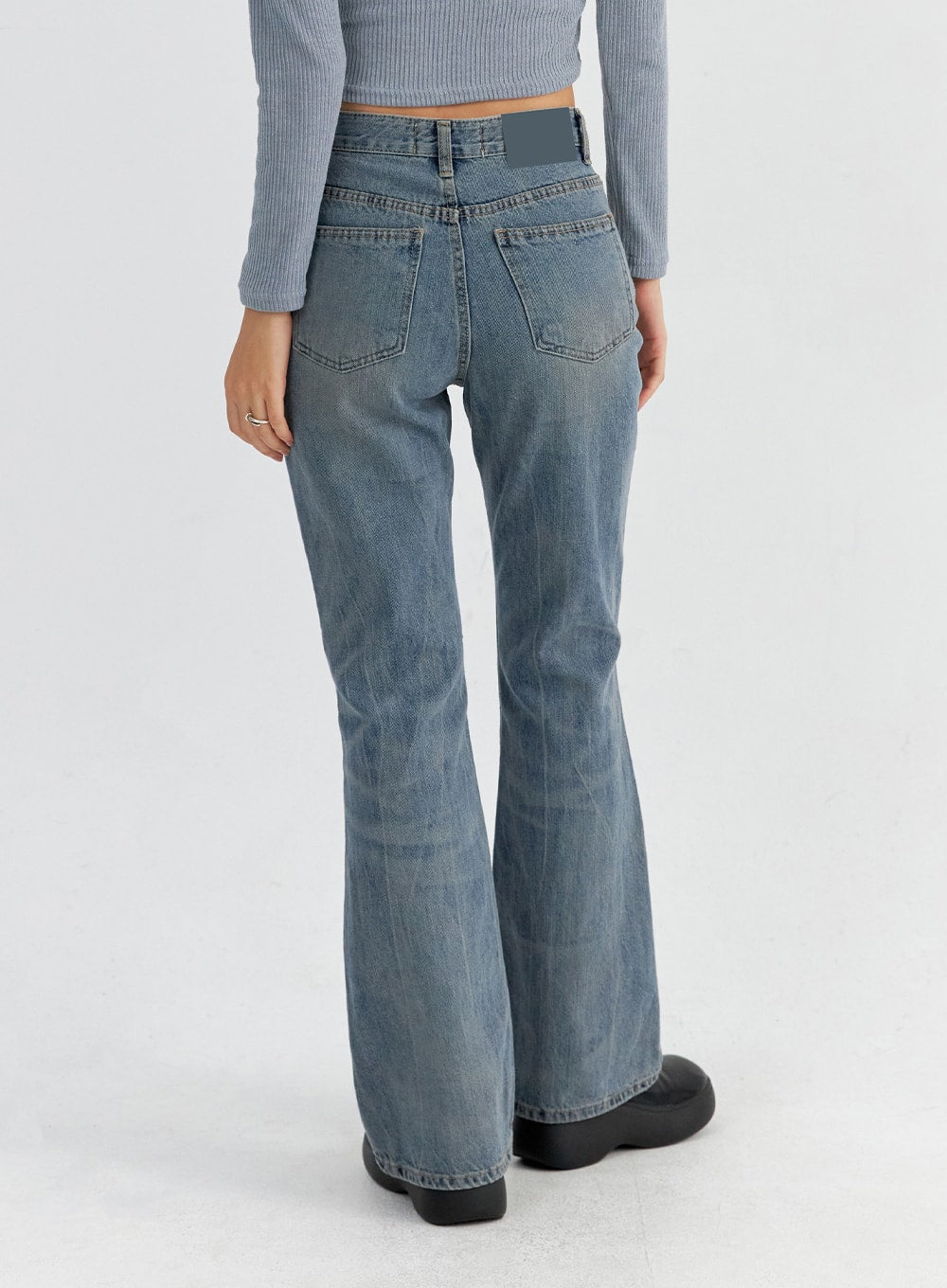 Vintage Washed Bootcut Jeans CO325 in blue, back mid-body close-up on model, dual back pockets with contrast stitching, patch label at waistband, bootcut flare hem detail.