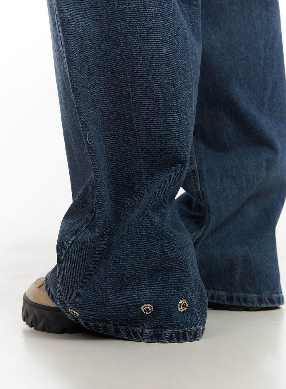 Bri Oversized Buttoned Baggy Jeans CF518 in dark blue, close-up of hem detail showing metal eyelet snap buttons at cuff, extra-long wide leg pooling over chunky sandals.
