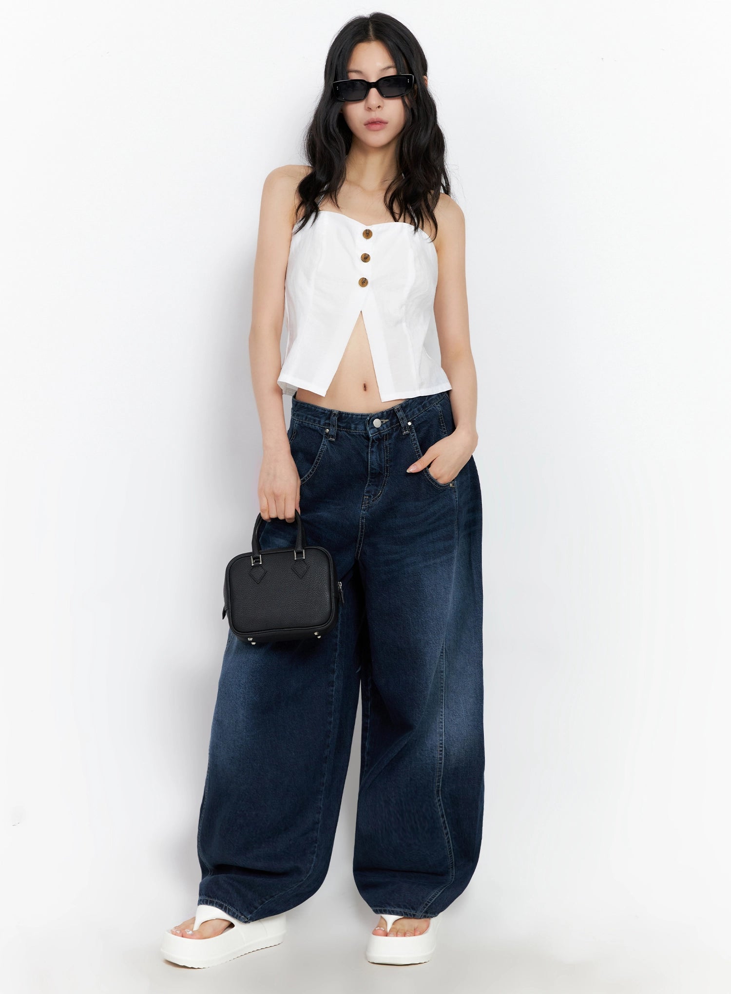 Sohee Angel Wing Print Wide-Leg Jeans IG508 in dark blue, full front view on model holding black mini bag, wide-leg washed cotton denim with front pockets, paired with white halter top and sunglasses.