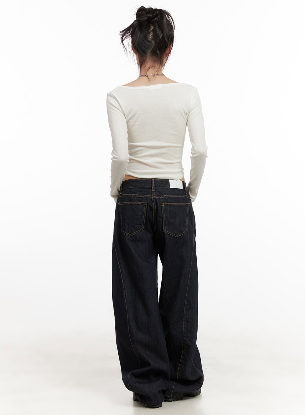 Fernanda Balloon-Fit Baggy Jeans CJ502 in dark blue, full back view on model, low-waist baggy cotton denim with contrast stitch and brand label at waistband, wide ballooned leg, styled with white long-sleeve top.