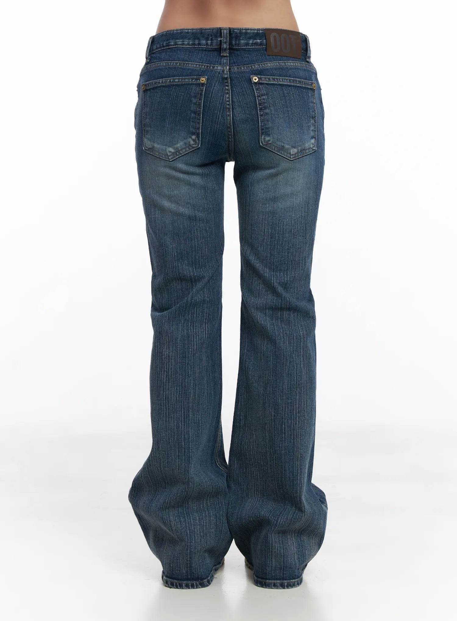 Astrid Low Rise Flared Bootcut Jeans CJ514 in blue, back view on model (waist-to-hem), back patch pockets with stitching, low-rise waistband, flared hem in washed cotton-spandex denim.