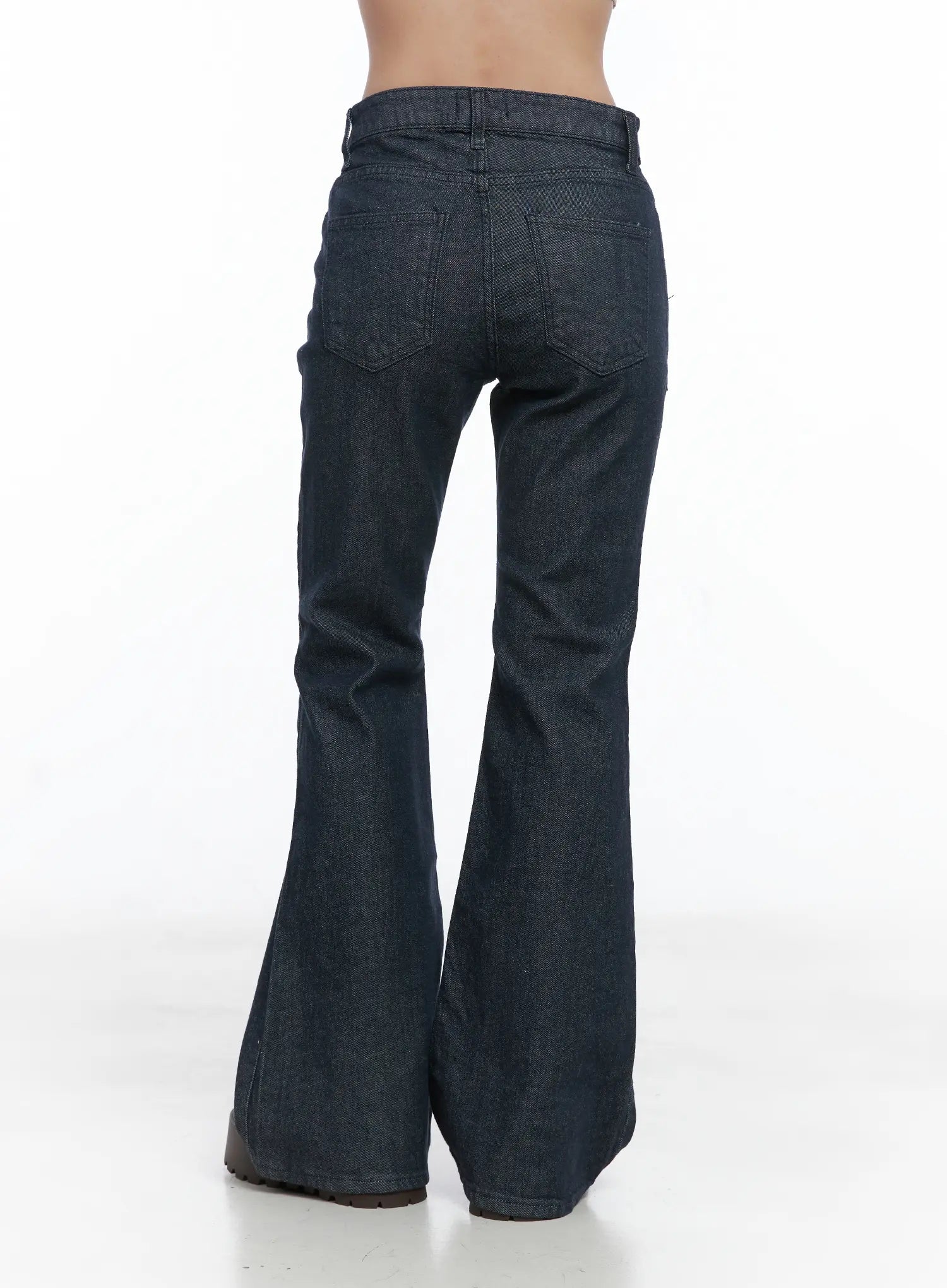 Kinley Flare Jeans CS502 in dark indigo, back view on model, wide bell flare hem, back patch pockets, smooth denim with subtle twill weave texture.