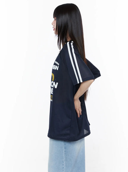 Oversized Sporty Graphic Tee CU519 in dark blue, side close-up on model, highlighting white double side stripes, semi-sheer mesh fabric texture, and relaxed oversized length over a denim skirt.