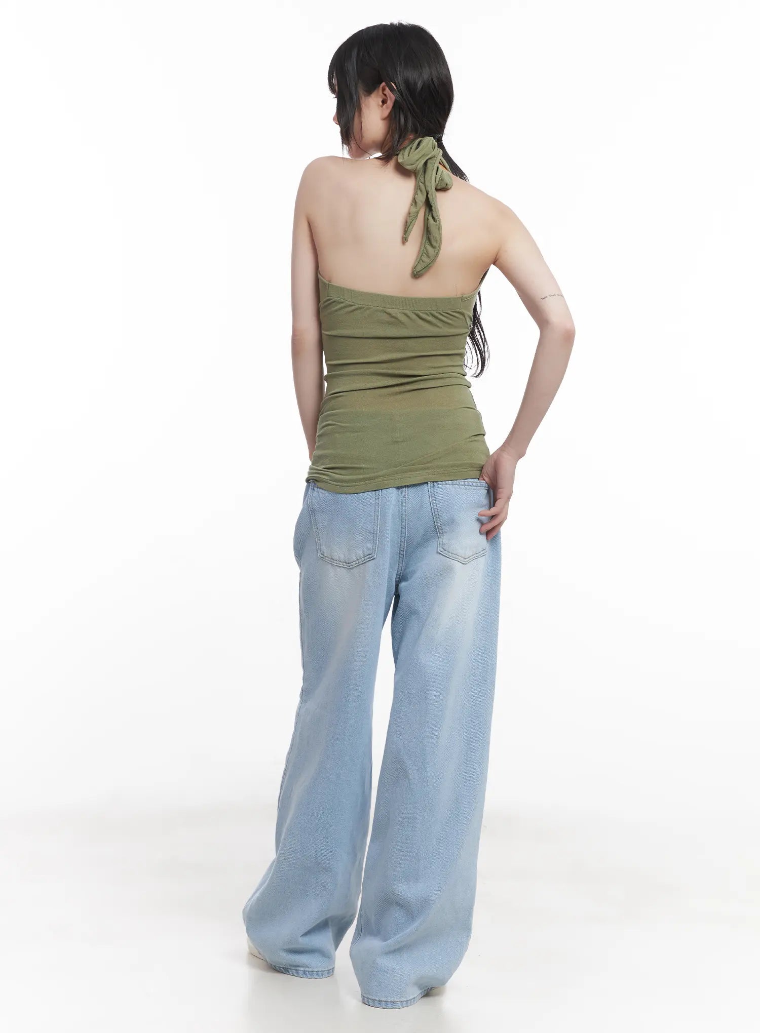 Haerin Washed Wide-Leg Jeans CU519 in light blue, full back view on model, dual back pockets with contrast stitching, washed wide-leg silhouette, paired with olive halter top.