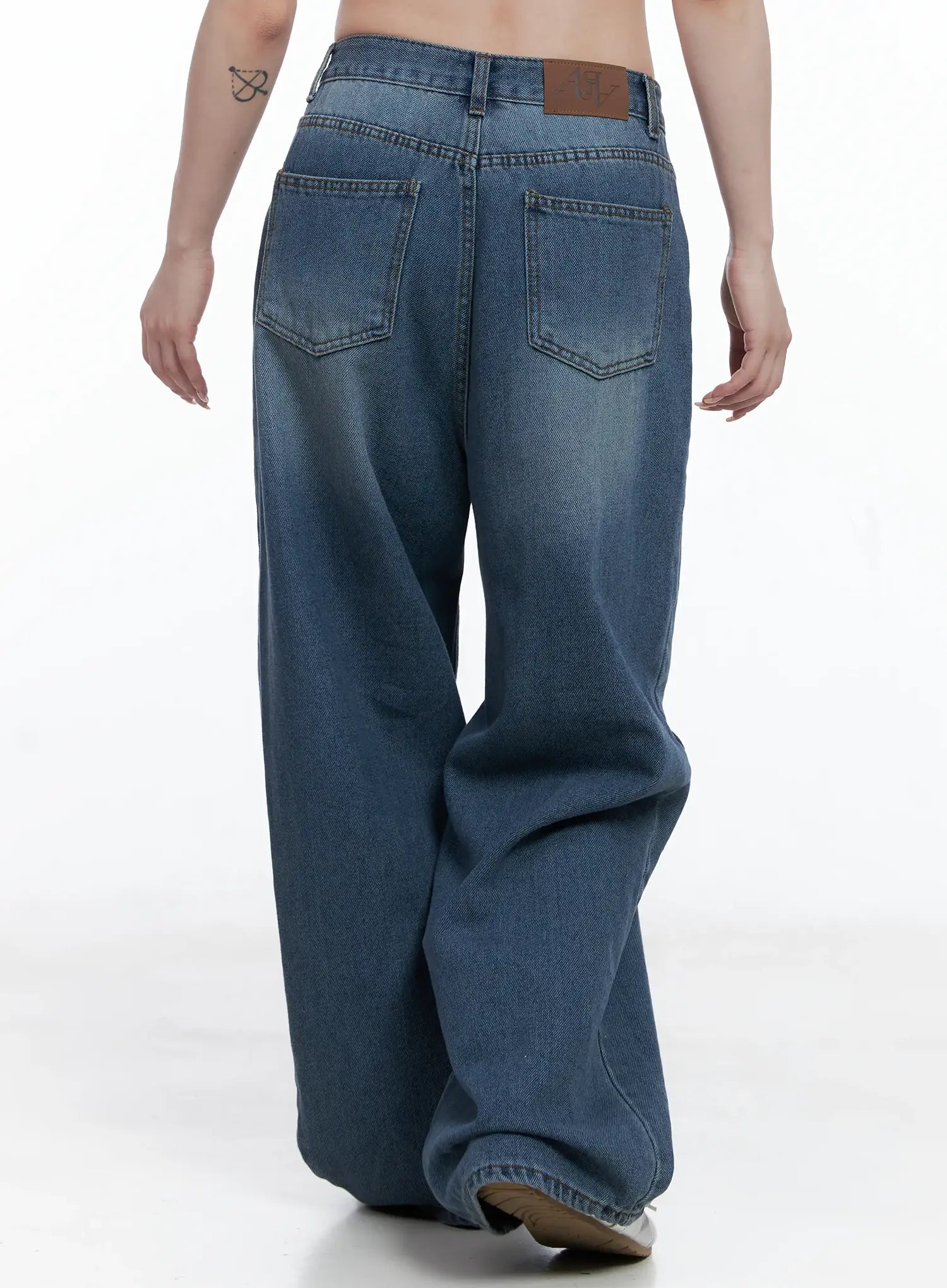 Margot Low-Rise Washed Wide-Leg Jeans CS501 in dark blue, back close-up on model, rear patch label and stitched back pockets with washed fading detail visible.