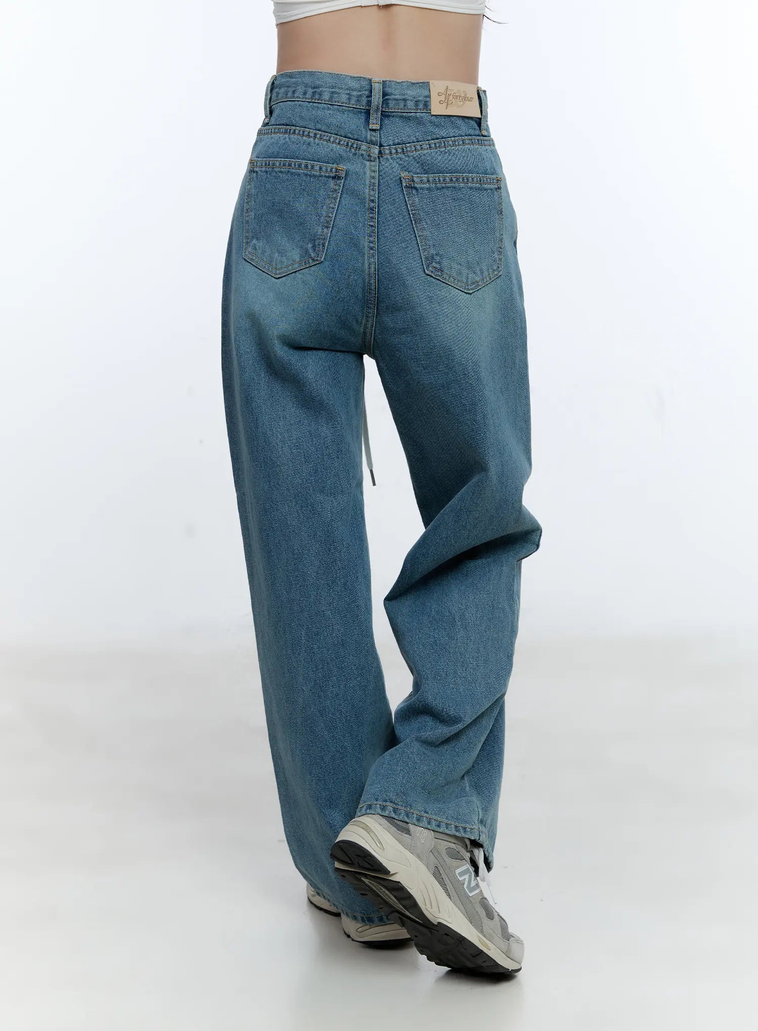 High-Waist Wide-Leg Drawstring Jeans CG513 in blue, back close-up on model, showcasing dual back pockets, brand label patch, washed denim texture, and dangling white drawstring.