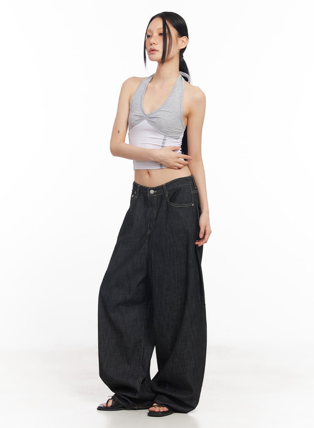 Elvie Baggy Jeans CY528 in black, side-angle full-length shot on model, exaggerated wide-leg silhouette with contrast topstitching, paired with a crop halter top.