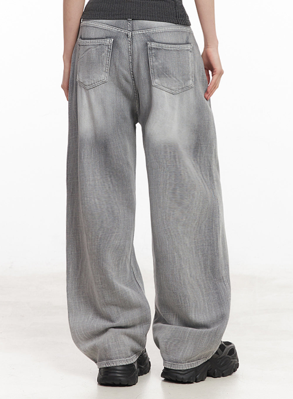 Flore Washed Wide-Leg Jeans IY516 in gray, back view on model, dual back patch pockets with washed fading across wide leg, paired with dark ribbed top and black sneakers.