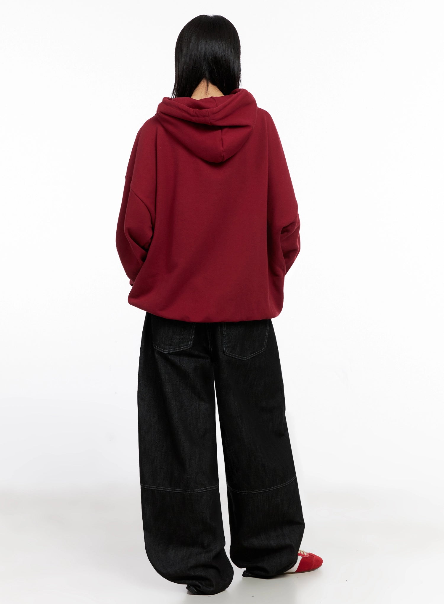 Leyla Pin-Tuck Wide-Leg Jeans IS515 in black, back view on model in red hoodie, contrast-stitched patch pockets and wide-leg volume visible from behind, red sneakers below.