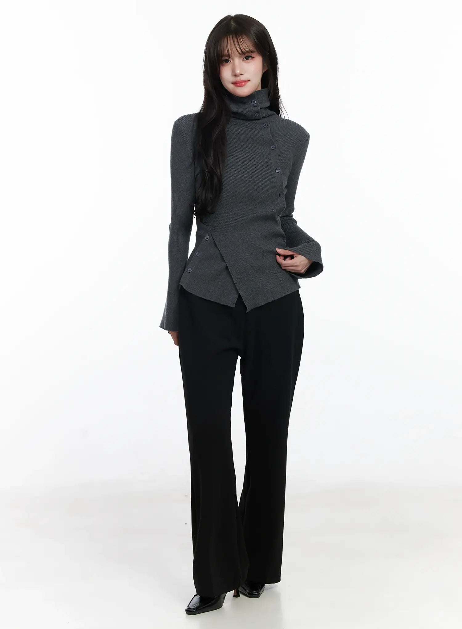 Hip Pad Slacks IJ529 in black, slight front-angle full-body on model, feminine slim bootcut fit, high waist, styled with asymmetric grey knit top.