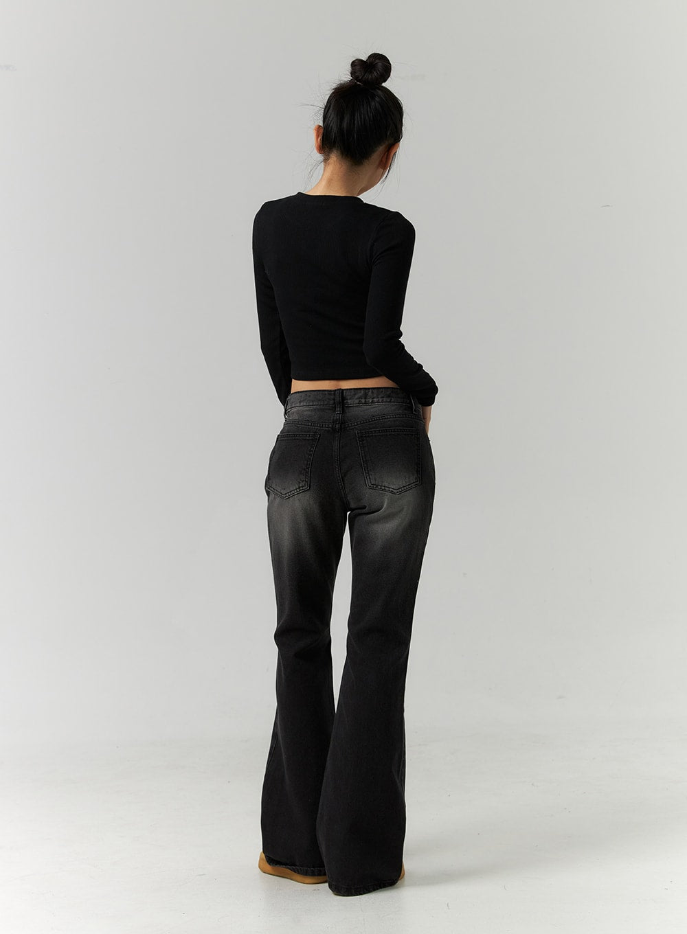 Low Rise Bootcut Jeans CD304 in black, full-length back view on model, rear pockets and washed denim fade visible, bootcut flare from knee to hem, paired with black crop top.